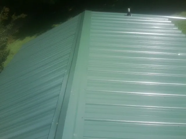 New green metal panels meeting at the ridge of a roof — Flat Roof Repair work by our crew in Reno