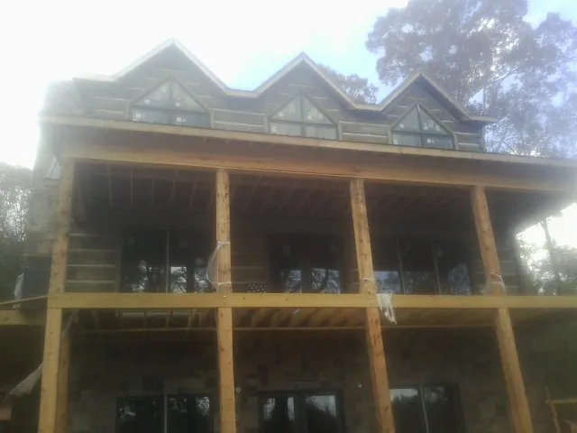 Dormers and porch framing on a large log home under construction — Roof Coating work by our crew in Reno