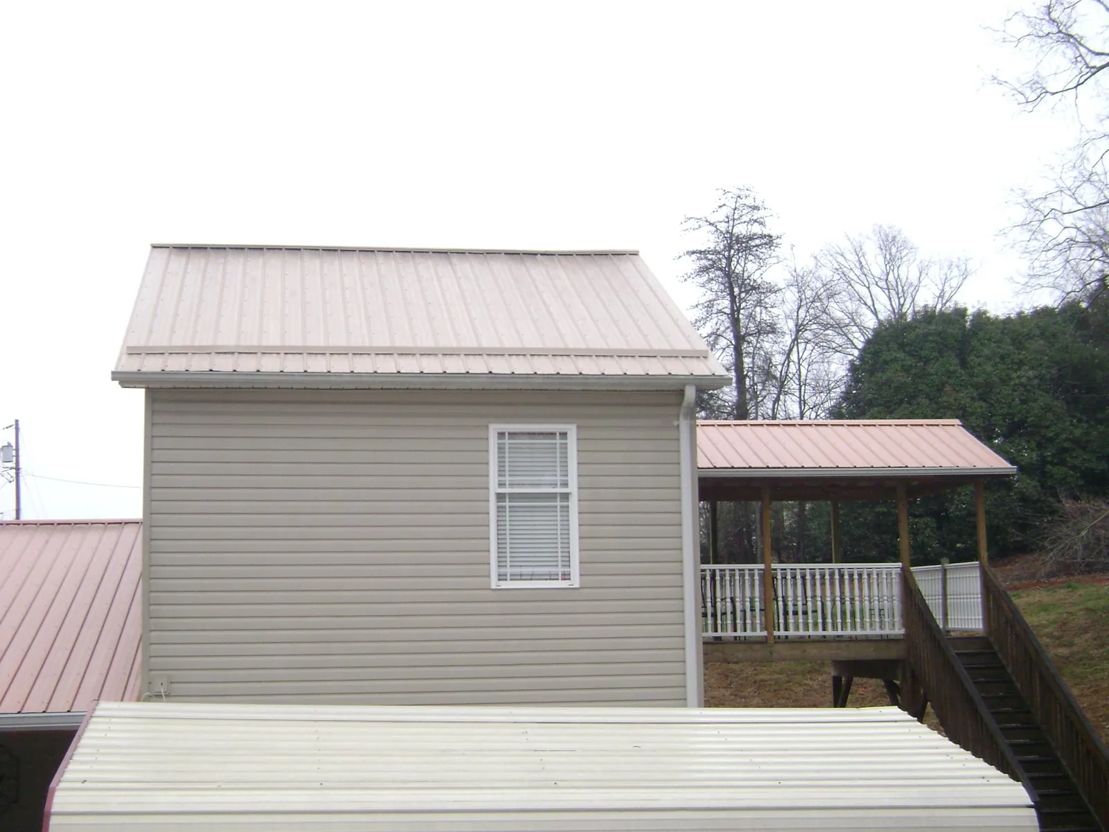Tan metal roofs on a two story addition and attached porch, from a Roof Replacement job in Reno